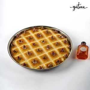 Authentic plain basboosa dessert in round tray garnished with rose buds from Gateau Gourmet Cafe