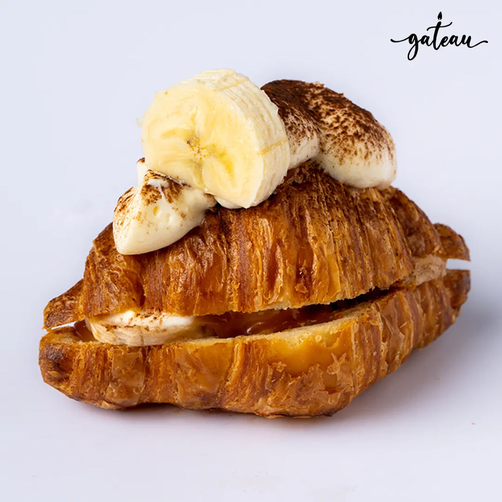 Banoffee croissant from Gateau Gourmet Cafe topped with banana slices and cream on flaky golden pastry