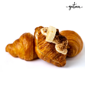Gateau Gourmet Cafe Banoffee croissant topped with banana slice and cream on a white background