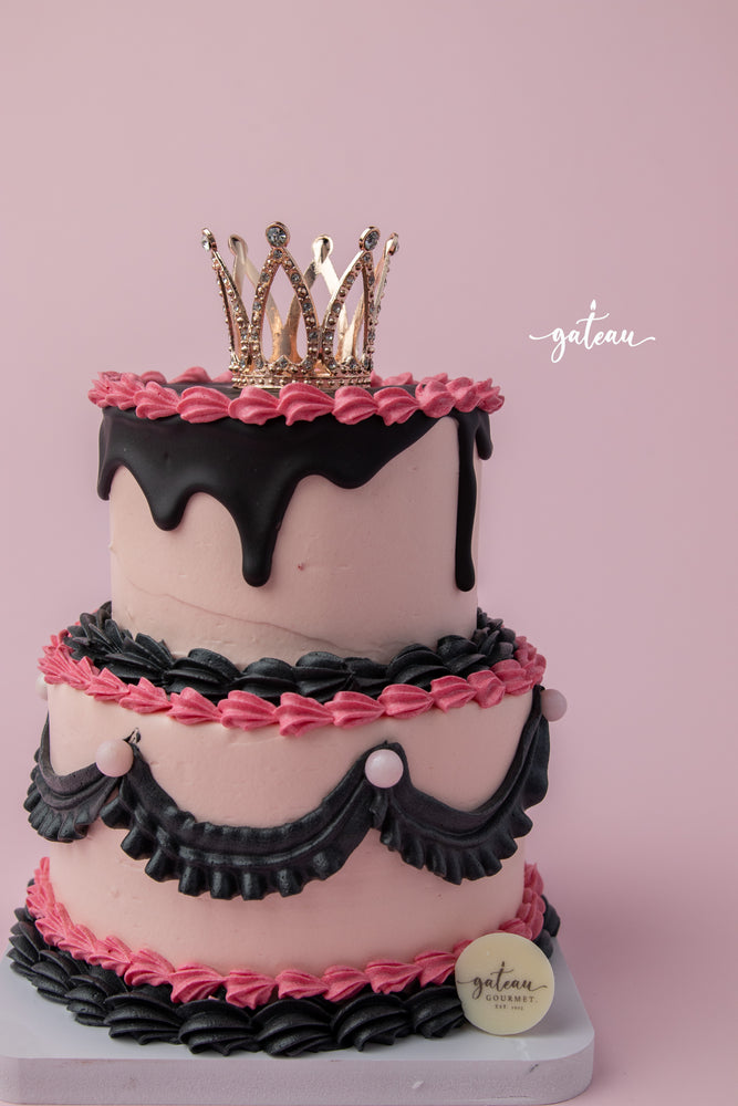 Gateau Gourmet Cafe Barbie birthday cake with pink frosting black drip and decorative crown topper