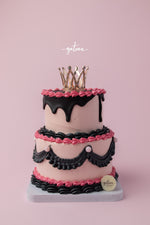 Gateau Gourmet Cafe Barbie birthday cake with pink frosting black decorations and a gold crown topper
