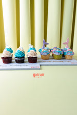 Cupcakes from Gateau Gourmet Cafe featuring beach inspired cupcake flavors with blue and pink frosting and decorative toppers