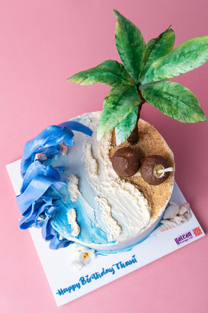 Beach theme cake by Gateau Gourmet Cafe featuring palm tree, blue waves, and sandy shore design