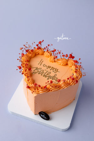 Heart-shaped birthday cake from Gateau Gourmet Cafe with orange frosting for birthday cake delivery service