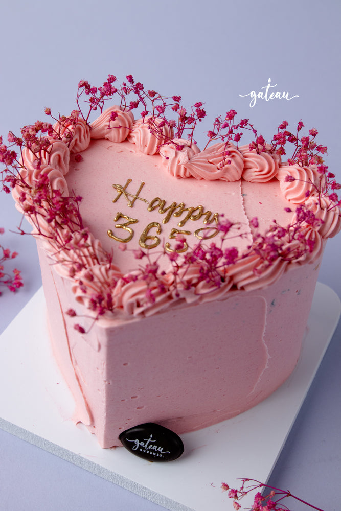 Heart-shaped pink birthday cake with floral decorations available for birthday cake delivery service