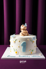 Birthday cake with fondant decorations featuring a number one and a fondant puppy on top by Gateau Gourmet Cafe