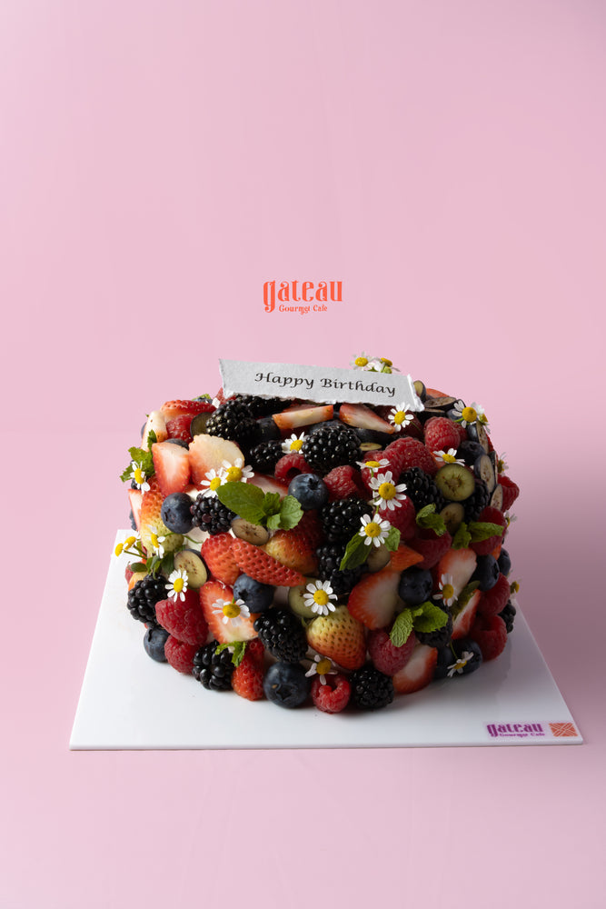 Delicious birthday cake with mixed berries, adorned with fresh fruits and flowers for a festive celebration