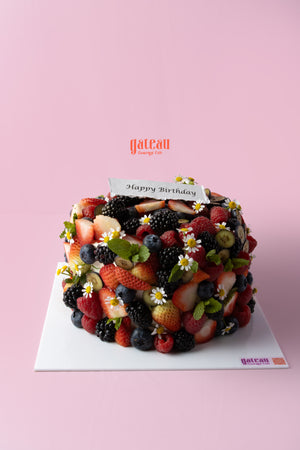Delicious birthday cake with mixed berries, adorned with fresh fruits and flowers for a festive celebration