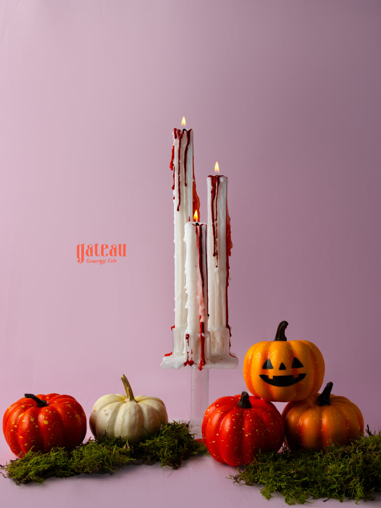 Bloody Halloween candles on a display with decorative pumpkins for festive decor