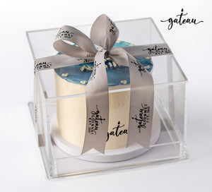Blue ombre cake in a clear gift box with gray Gateau Gourmet Cafe branded ribbon