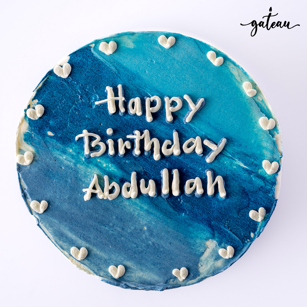 Blue ombre cake with Happy Birthday Abdullah written in white icing and small heart decorations