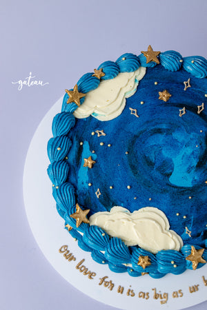 Gateau Gourmet Cafe blue sky cake design with blue frosting, white clouds, and gold star decorations
