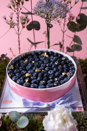 Gateau Gourmet Cafe blueberry cheesecake with floral arrangement topped with fresh blueberries and gold accents
