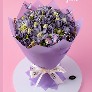 Purple bouquet cake for special occasions with intricate flower designs and edible butterflies wrapped in purple paper