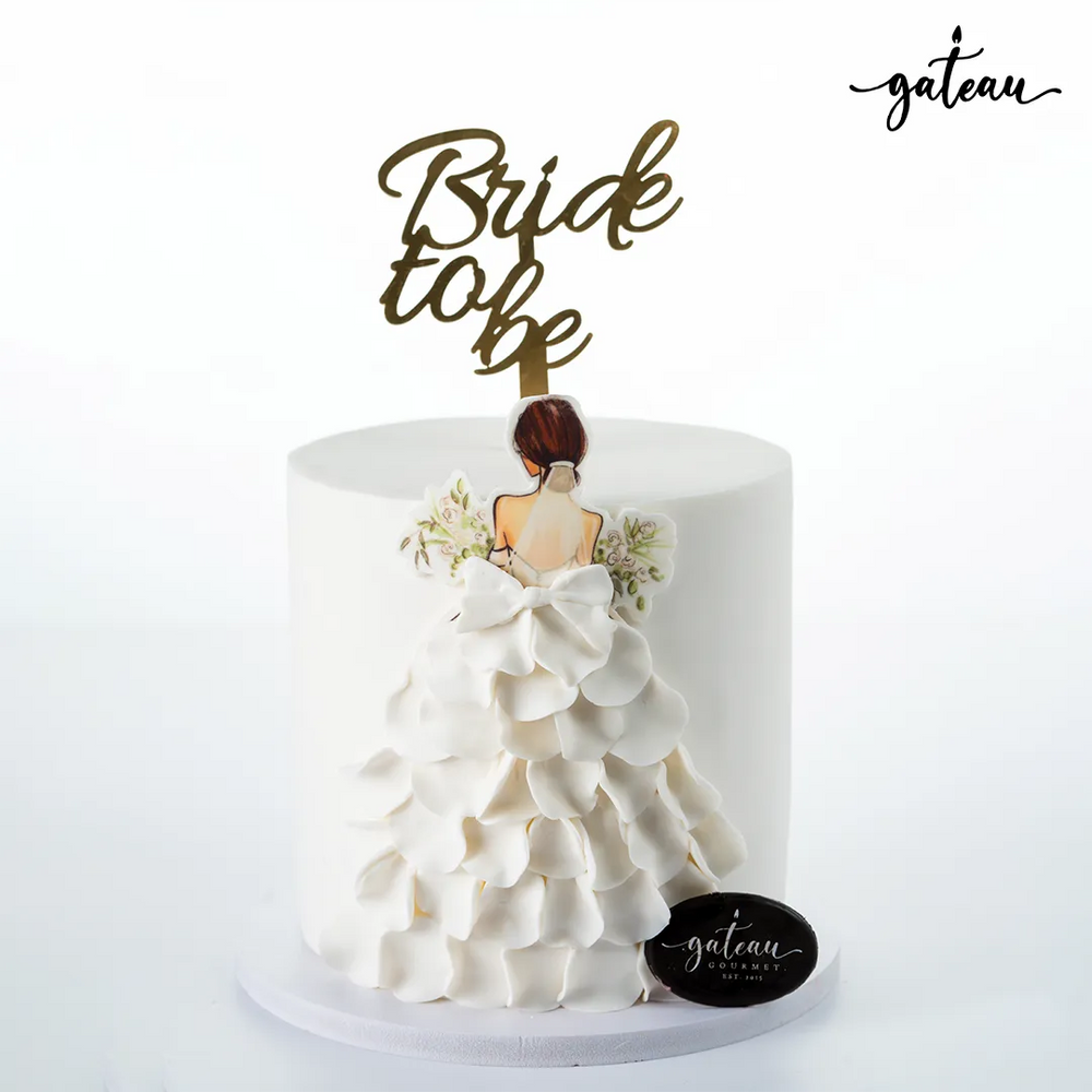 Elegant bride to be cake with white ruffled dress design and gold topper by Gateau Gourmet Cafe