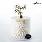 Elegant bride to be cake with white ruffled dress design and gold topper by Gateau Gourmet Cafe