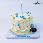 Buttercream celebration cake with intricate white and blue floral designs from Gateau Gourmet Cafe