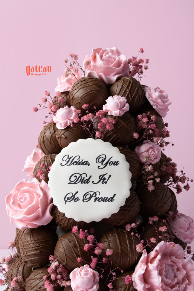 Chocolate truffle tower cake decorated with pink roses and a celebratory message on top