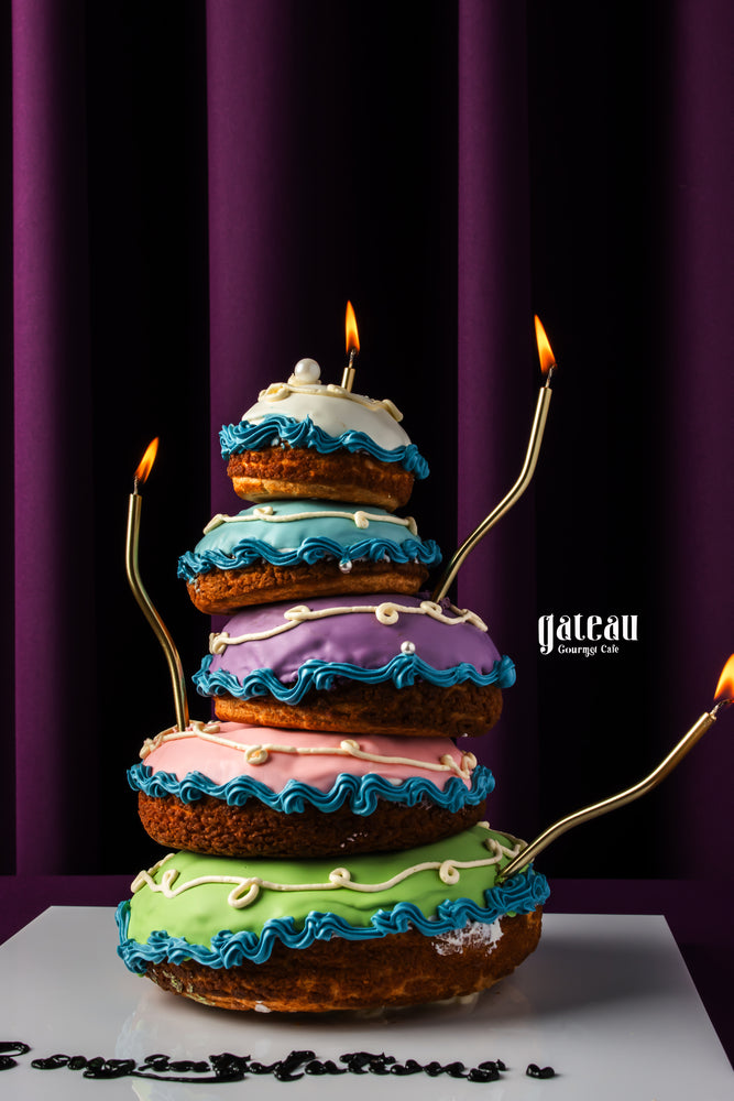 Choux pastry stand with colorful layered choux pastries decorated with blue icing and gold accents from Gateau Gourmet Cafe
