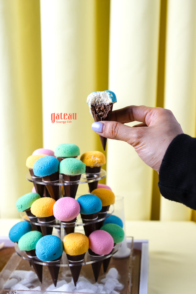 Colorful cupcakes for summer party displayed on a tiered stand with a hand holding one cupcake