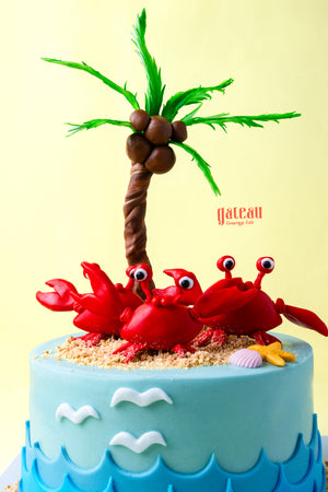 Gateau Gourmet Cafe crab birthday cake design with red crabs, palm tree, and ocean waves decoration