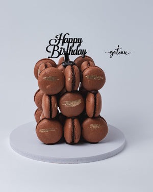 Cube-shaped macaroons stack with chocolate filling and gold leaf accents topped with Happy Birthday sign