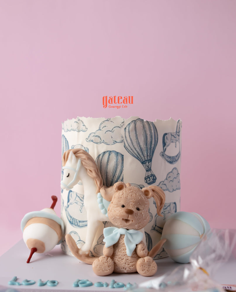 Custom baby shower cake featuring a horse, teddy bear, and blue hot air balloons for celebrations