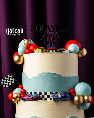 Two-tier custom cake for boys decorated with toy cars and vibrant colors from Gateau Gourmet Cafe