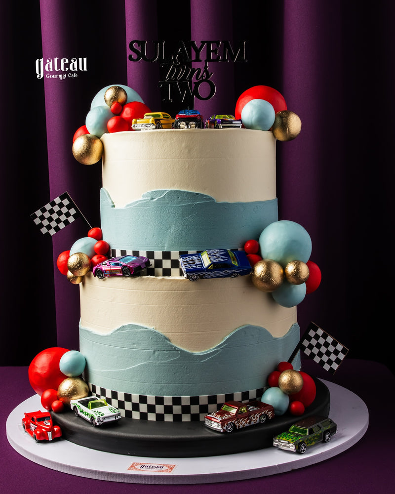 Custom cakes for boys featuring a two-tiered car-themed design with race cars and colorful decorations