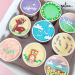 Nine custom decorated cups featuring colorful designs and personalized names from Gateau Gourmet Cafe