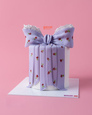 Elegant custom designed cakes by Gateau Gourmet Cafe featuring a white cake with a large purple bow and floral details