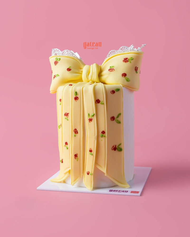 Custom designed cakes by Gateau Gourmet Cafe featuring a yellow bow decorated with small red roses