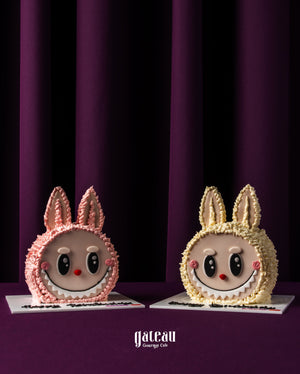 Two custom labubu cake designs from Gateau Gourmet Cafe featuring cute bunny faces in pink and yellow
