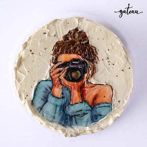 Custom photo cakes featuring a hand-painted image of a woman with a camera on creamy frosting