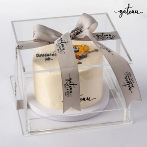 Custom SpongeBob cake presented in a clear box with a decorative ribbon from Gateau Gourmet Cafe