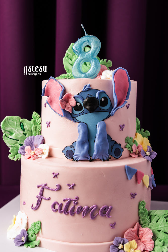 Gateau Gourmet Cafe custom Stitch themed cake with pink frosting and colorful floral decorations