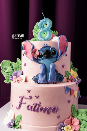 Gateau Gourmet Cafe custom Stitch themed cake with pink frosting and colorful floral decorations