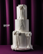 Three-tier white elegant custom wedding cakes with ribbon decorations by Gateau Gourmet Cafe