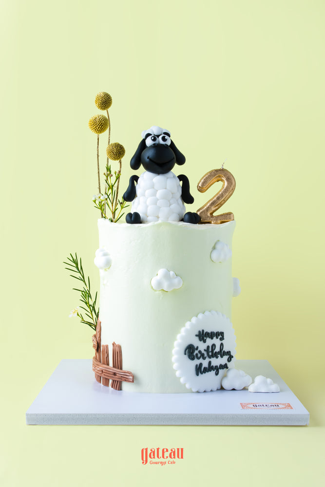 Cute sheep cake for kids with a black sheep topper and decorative flowers for a birthday celebration