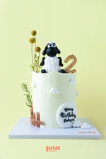 Cute sheep cake for kids with a black sheep topper and decorative flowers for a birthday celebration