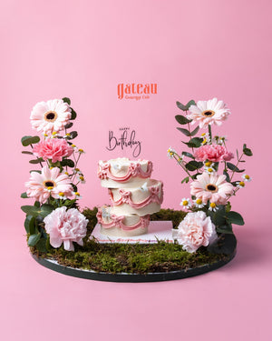Gateau Gourmet Cafe decorative cake arrangement with pink flowers and layered white cake on green moss