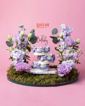 Gateau Gourmet Cafe decorative cake arrangement with purple floral decorations on moss base for birthday