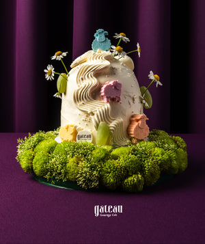 Gateau Gourmet Cafe Eid Al Adha cake ideas with white frosting, colorful sheep decorations, and green floral base