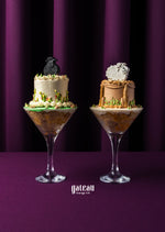 Two elegant Eid Al Adha cakes by Gateau Gourmet Cafe displayed in tall glass dessert cups with decorative sheep toppers