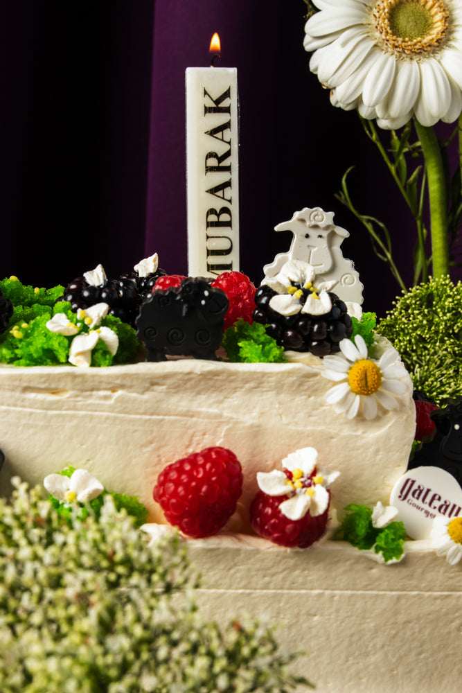 Eid special floral cake by Gateau Gourmet Cafe decorated with fresh berries, white flowers, and a Mubarak candle