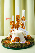 Elegant summer celebration cake by Gateau Gourmet Cafe decorated with dried orange slices, candles, and white frosting