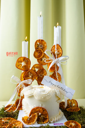 Gateau Gourmet Cafe elegant summer celebration cake decorated with white frosting and dried orange slices