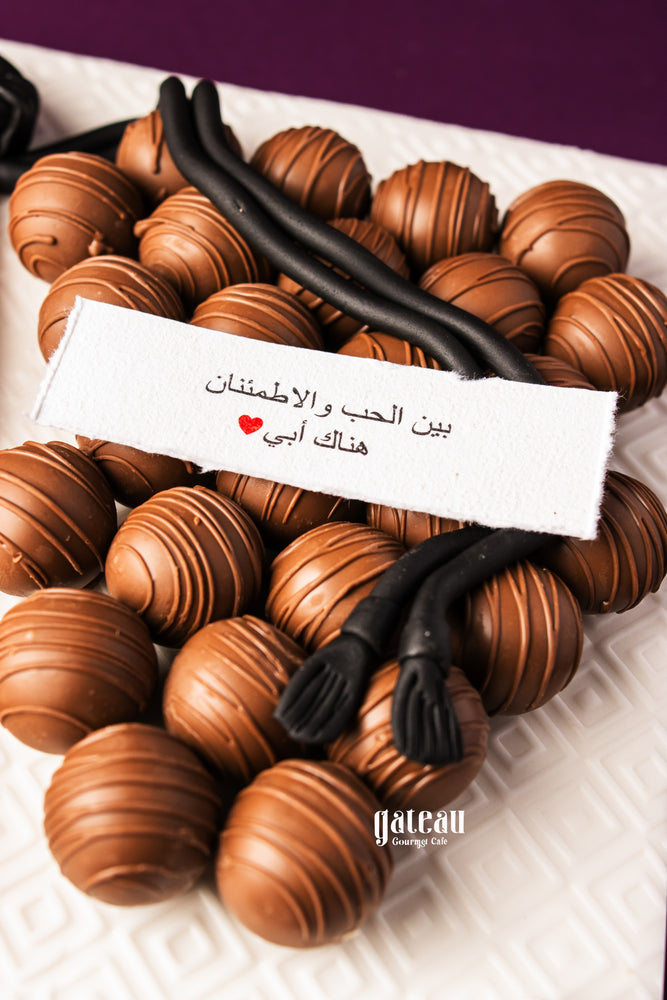 Father's Day chocolate truffles from Gateau Gourmet Cafe arranged with decorative black licorice on a white plate