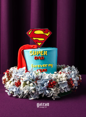 Father's Day mini cake by Gateau Gourmet Cafe decorated with Superman emblem and surrounded by flowers