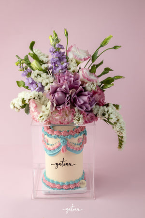 Gateau Gourmet Cafe floral cake arrangement with pastel pink, purple, and white flowers on decorated cake